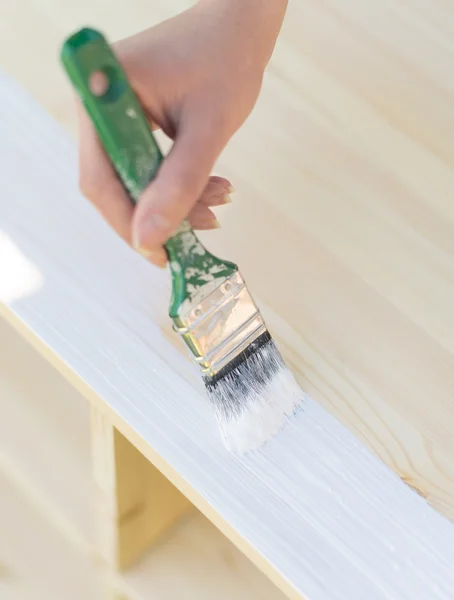 Kvinnlig hand med penseln målar trämöbler. — Stockfoto