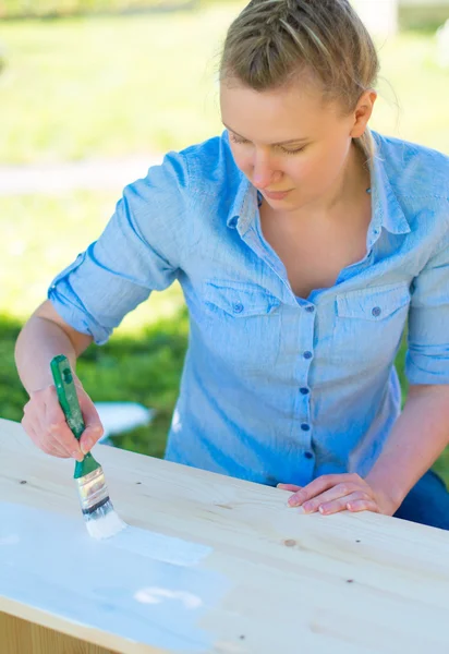 Kobieta z pędzli malarstwo meble drewniane. — Zdjęcie stockowe