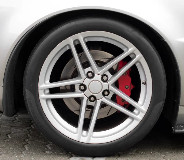 Silver sports car wheel on the road. — Stock Photo, Image
