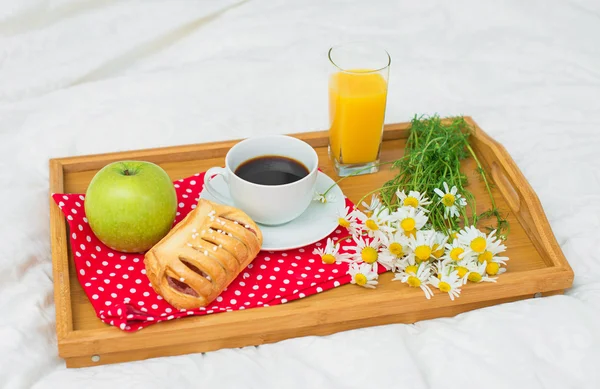 Breakfast in bed. Coffee, bun, apple and orange juice.