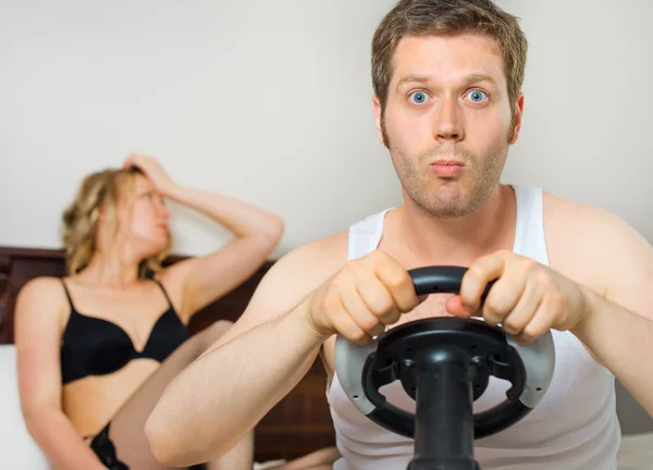 Dipendenza da videogiochi. Uomo giocare video gioco con volante, donna sconvolta sullo sfondo . — Foto Stock