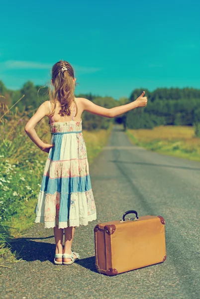 Little girl with vintage suitcase on rural road. — Stock Photo, Image
