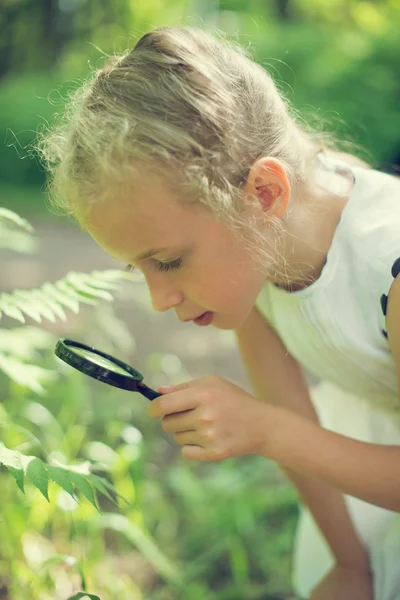 Petite fille examinant la nature à travers la loupe . — Photo