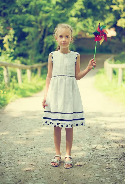 Kleines Mädchen mit buntem Windrad im Park. — Stockfoto