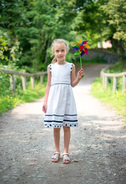 Kleines Mädchen mit buntem Windrad im Park. — Stockfoto