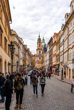 Prag, Çek Cumhuriyeti - 08.05.2025: St. Nicholas Kilisesi ile kalabalık kaldırım taşı caddesi Lazenska.