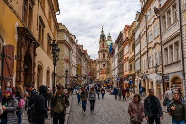 Prag, Çek Cumhuriyeti - 08.05.2025: St. Nicholas Kilisesi ile kalabalık kaldırım taşı caddesi Lazenska.