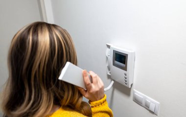 Bir kadın ev telefonundan konuşuyor..