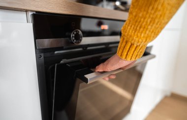 Kadın pişirmeye başlamak için fırını açar..