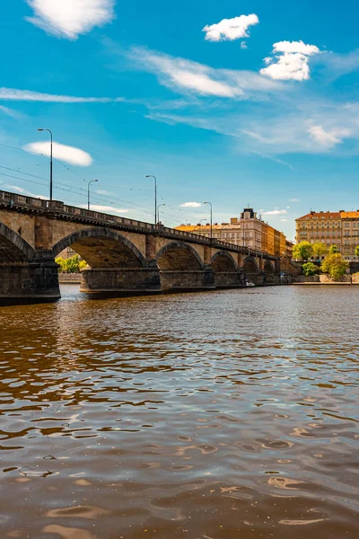 Palacky Köprüsü. Tarihi taş köprünün altında binalarla gezen tekneler.