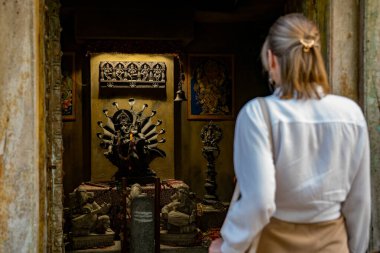Woman visiting ancient Hindu temple shrine.