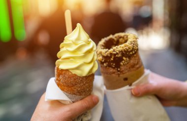 Two traditional Czech trdelnik pastries in hands.