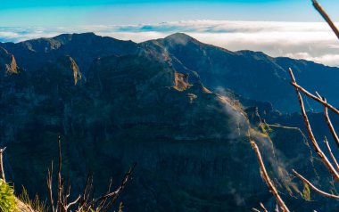 Altın güneş ışığı karanlık sivri dağ tepelerine vuruyor..