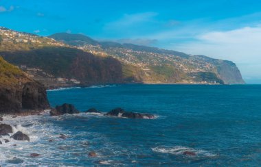 Sarp kayalıkları ve turkuaz okyanusuyla dramatik kıyı manzarası.