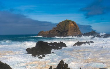 Köpüklü okyanusta deniz feneri olan büyük volkanik kayalar..