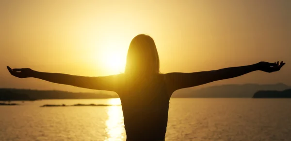 Vrouw met armen wijd open bij zonsondergang. — Stockfoto