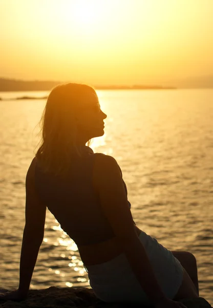 Silhouette einer Frau, die sich vor Sonnenuntergang entspannt. — Stockfoto