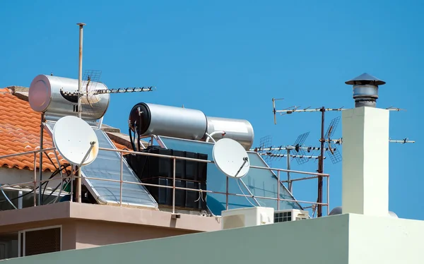 Solar water heating system and satellite television dishes on the rooftops. — Stock Photo, Image