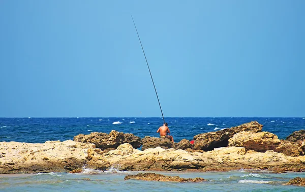 Rapaz pesca em rochas junto ao mar . — Fotografia de Stock