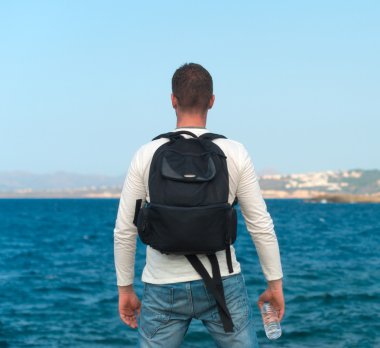 Sırt çantası konumu denize yakın olan erkek turist. Metniniz için yer.