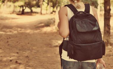 Ormanın içinde sırt çantası olan kadın. Arkadan görüntülemek.