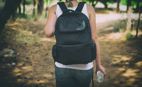 Kvinna med ryggsäck i skogen. Vy från baksidan. — Stockfoto