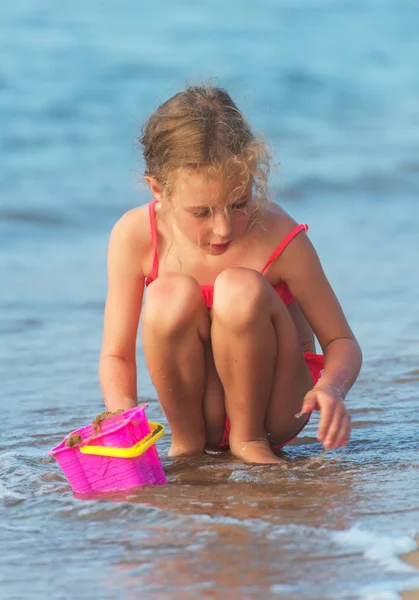 Kleines Mädchen spielt mit Sand am Strand. — Stockfoto