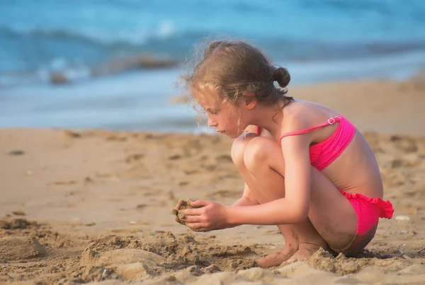 Meisje spelen met zand op het strand. — Stockfoto