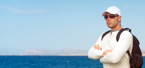 Turista masculino com mochila de pé perto do mar . — Fotografia de Stock