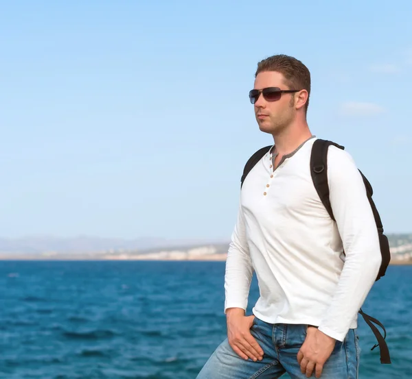 Manliga turist med ryggsäck står nära havet. — Stockfoto