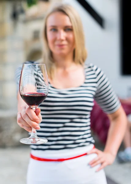 Женщина предлагает бокал красного вина на открытом воздухе . — стоковое фото