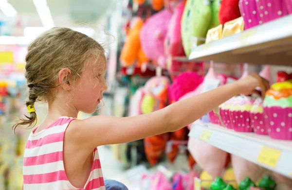 Niña seleccionando juguete en los estantes en el supermercado . —  Fotos de Stock