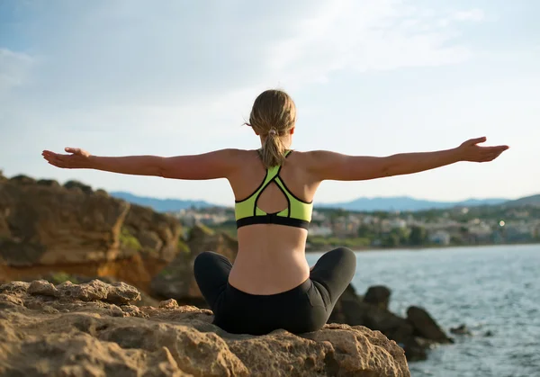 Jonge vrouw beoefenen van yoga in de buurt van de zee. — Stockfoto