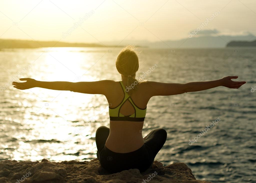 Young woman practicing yoga near the sea.