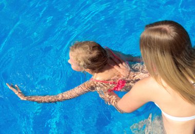 Küçük bir kıza yüzmeyi öğreten bir kadın. Metin için yer.