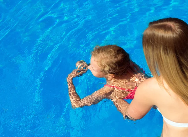 Woman teaching little girl to swim. Place for text.