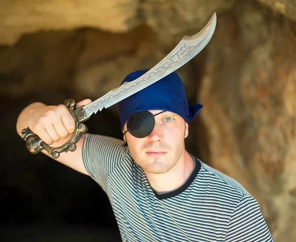 Mężczyzna piratem z mieczem w pobliżu wejście do jaskini. — Zdjęcie stockowe