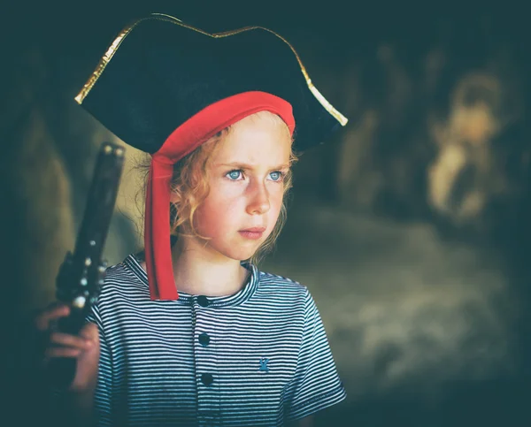 Little girl in pirate costume with musket gun near the cave entrance. Place for your text. — Stock Photo, Image
