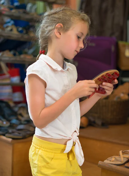 Маленькая девочка выбирает сандалии на рынке . — стоковое фото