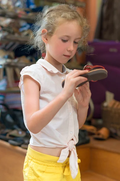 Meisje sandalen kiezen in de markt. — Stockfoto