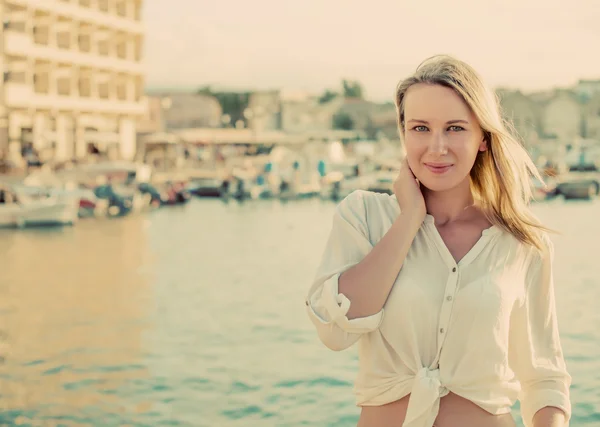 Vacker kvinna som står mot hamnen med båtar. — Stockfoto