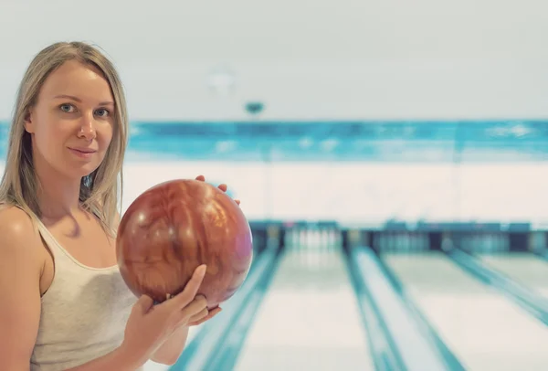 Hübsche Frau hält Ball im Kegelclub. — Stockfoto