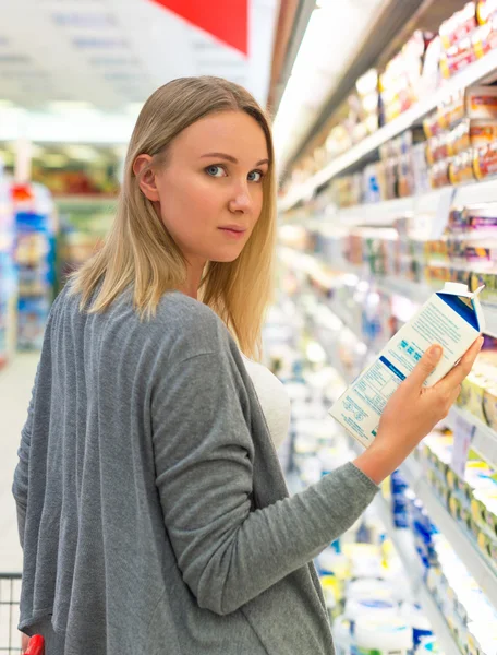 Vrouw kiezen van melk in de supermarkt. — Stockfoto