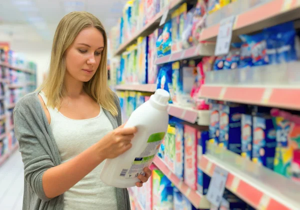 Vrouw kiest wasmiddel in kruidenier. — Stockfoto