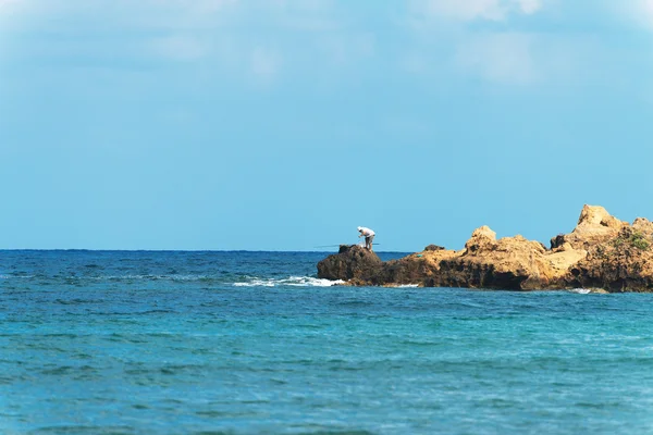 Homem pescando em rochas pelo mar . — Fotografia de Stock