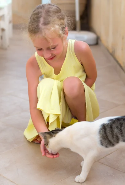 Pretty little girl feeding cat outdoor. — Stock Photo, Image