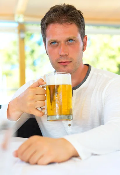 Knappe man met bier in zomer café. — Stockfoto