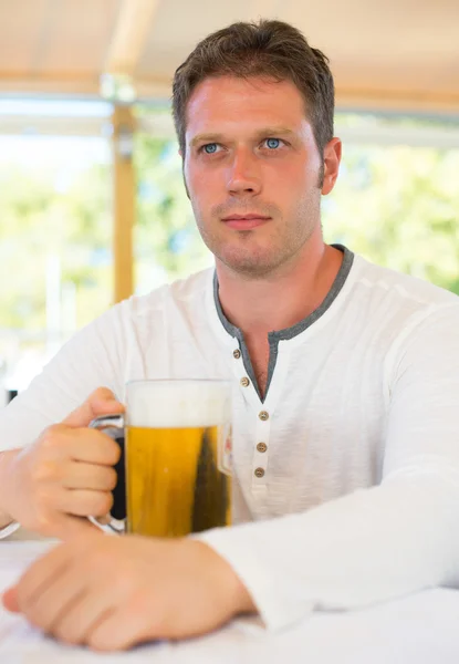 Pohledný muž s pivem v letní kavárně. — Stock fotografie