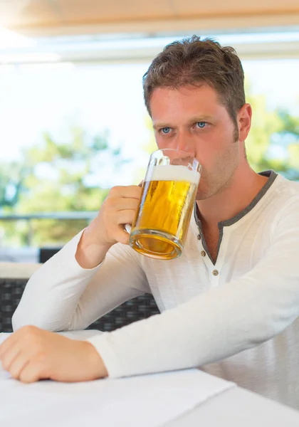 Schöner Mann trinkt Bier in Sommercafé. — Stockfoto