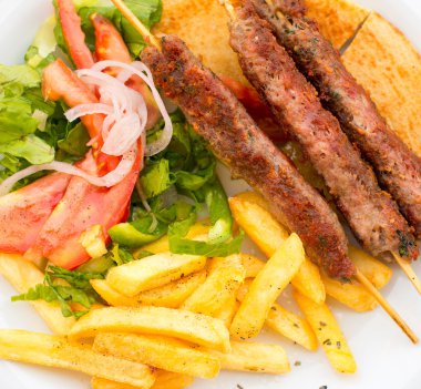 Souvlaki veya şiş patates ve sebze ile üzerinde kebap.